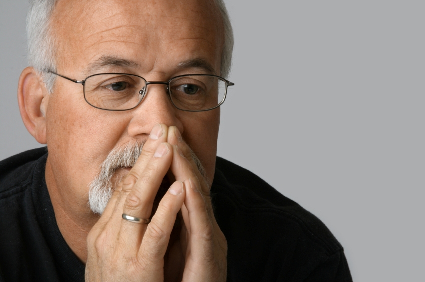 Concerned man stares into space with his face resting on his hand