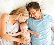 baby is laying down on the bed with the parents