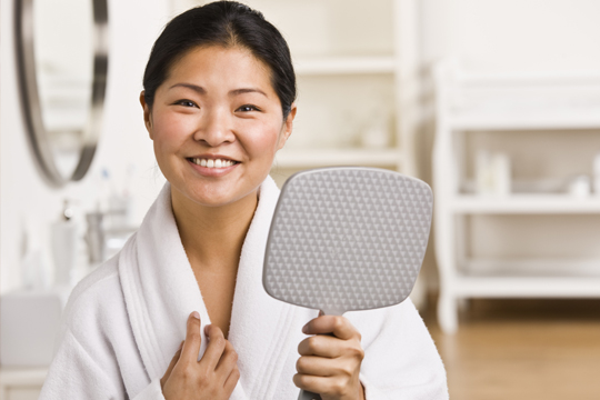 Woman holding mirror and smiling
