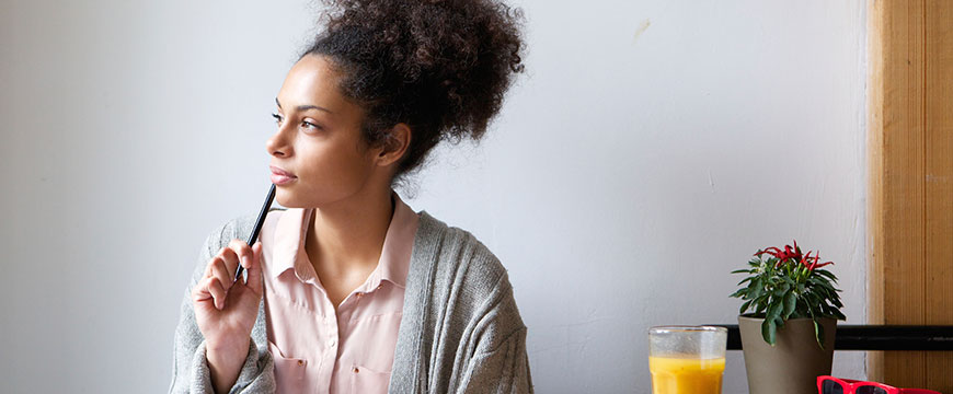 female is thinking while writing in her journal