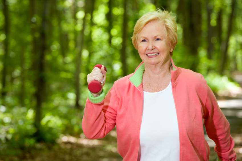 old woman is outdoors with a dumbbell