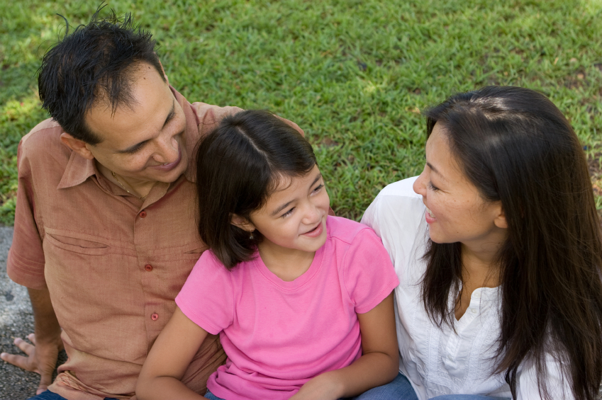 parents sitting with their child outdoors on grass