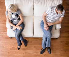 upset couple is sitting at opposite ends of the couch