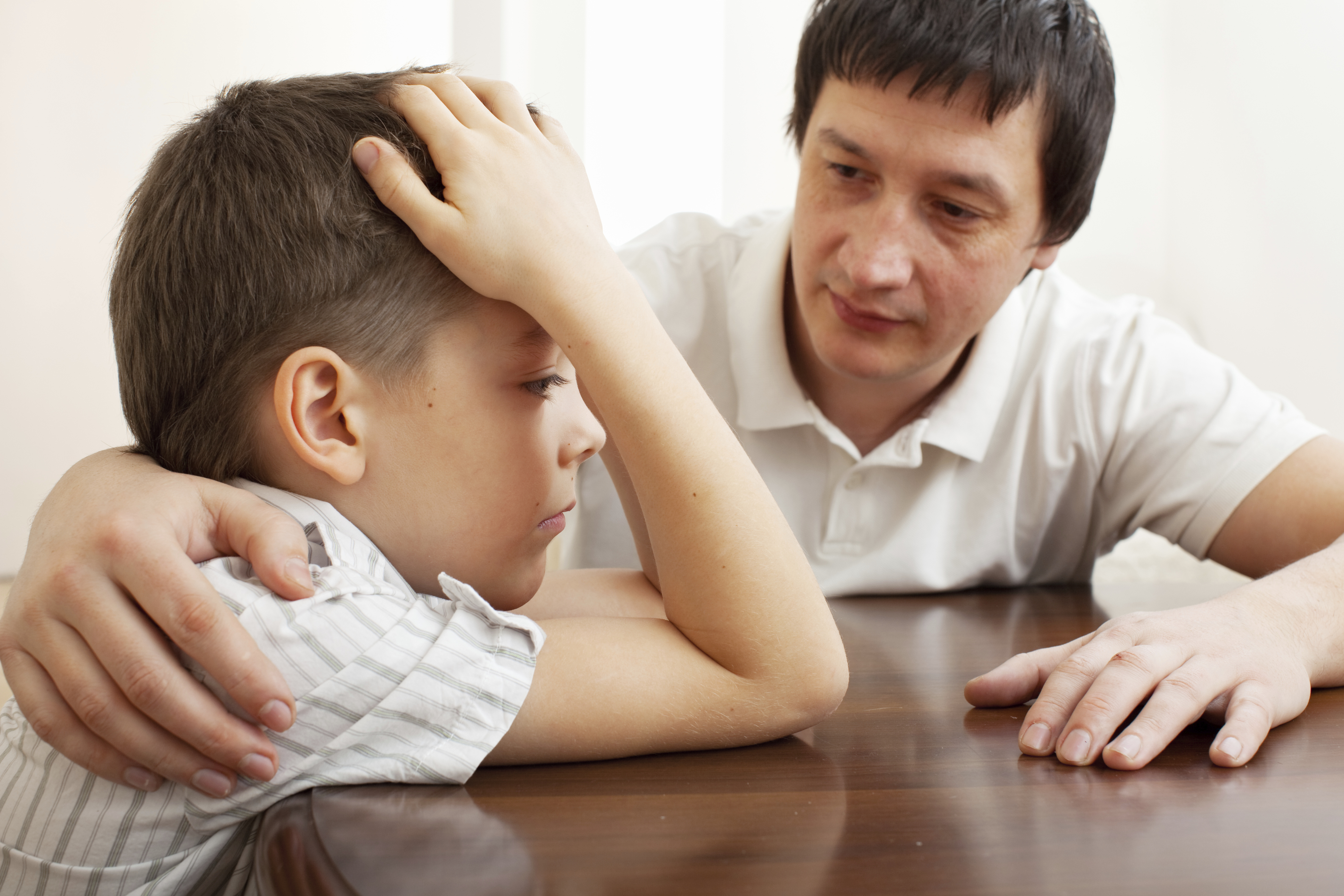 sad little boy being scolded by male adult