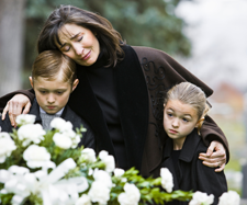 upset mother hugging her children at a funeral